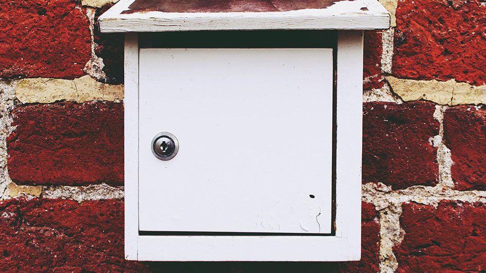 Ein weißer Briefkasten an einer roten Hauswand